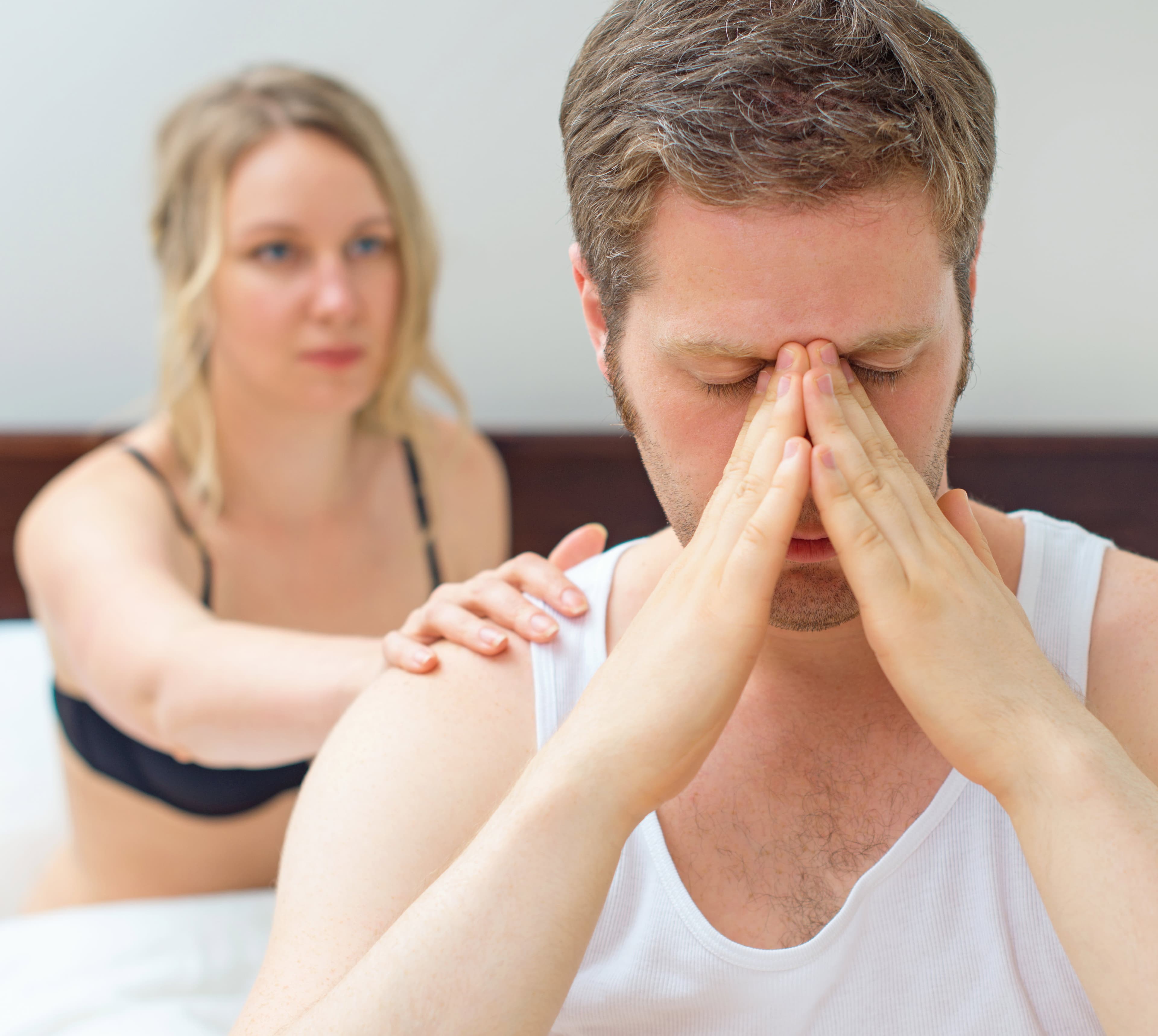 Man sitting with his face in his hands and his partner behind him.